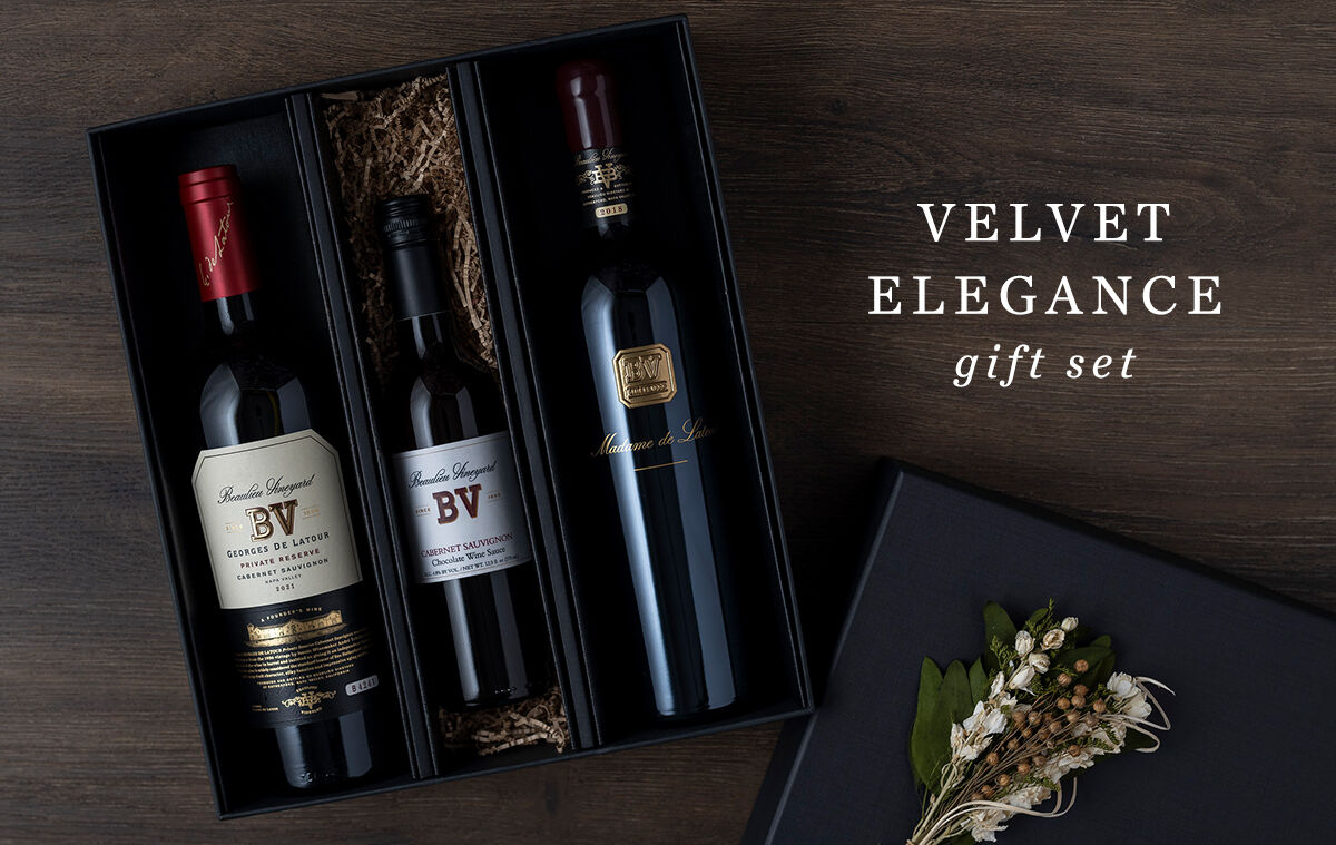 2 bottles of wine and chocolate sauce with dried flowers and a box.